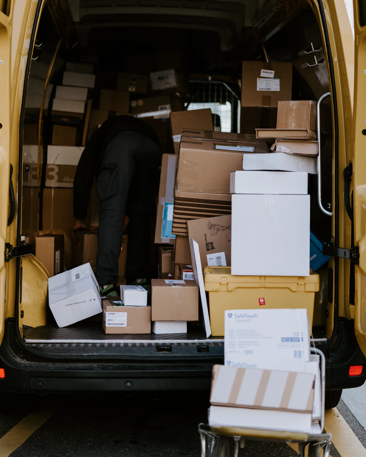 Open achterkant van een gele bestelbus vol pakketten